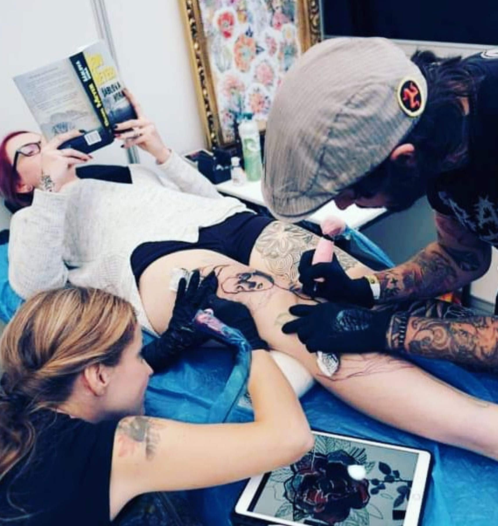 Dva tetovací umělci soustředěně pracují na tetování v zázemí tattoo studia na konvenci